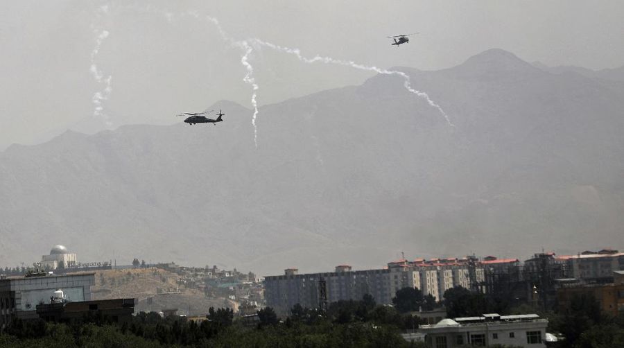 Anti-missile decoy flares are deployed as U.S. Black Hawk military helicopters and a dirigible balloon fly over the city of Kabul, Afghanistan, Sunday, Aug. 15, 2021. Taliban fighters entered the outskirts of the Afghan capital on Sunday and said they were awaiting a “peaceful transfer” of the city after promising not to take it by force, but amid the uncertainty panicked workers fled government offices and helicopters landed at the U.S. Embassy. (AP Photo/Rahmat Gul)