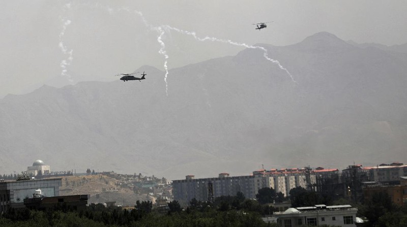 Anti-missile decoy flares are deployed as U.S. Black Hawk military helicopters and a dirigible balloon fly over the city of Kabul, Afghanistan, Sunday, Aug. 15, 2021. Taliban fighters entered the outskirts of the Afghan capital on Sunday and said they were awaiting a “peaceful transfer” of the city after promising not to take it by force, but amid the uncertainty panicked workers fled government offices and helicopters landed at the U.S. Embassy. (AP Photo/Rahmat Gul)