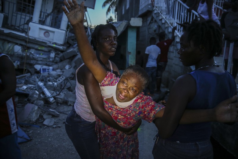 Haiti Earthquake People walk past a home destroyed by the earthquake in Les Cayes, Haiti, Saturday, Aug. 14, 2021. A 7.2 magnitude earthquake struck Haiti on Saturday, with the epicenter about 125 kilometers (78 miles) west of the capital of Port- au-Prince, the US Geological Survey said. (AP Photo/Joseph Odelyn)