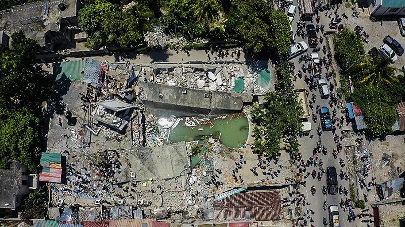 People walk past a home destroyed by the earthquake in Les Cayes, Haiti, Saturday, Aug. 14, 2021. A 7.2 magnitude earthquake struck Haiti on Saturday, with the epicenter about 125 kilometers (78 miles) west of the capital of Port- au-Prince, the US Geological Survey said. (AP Photo/Joseph Odelyn)