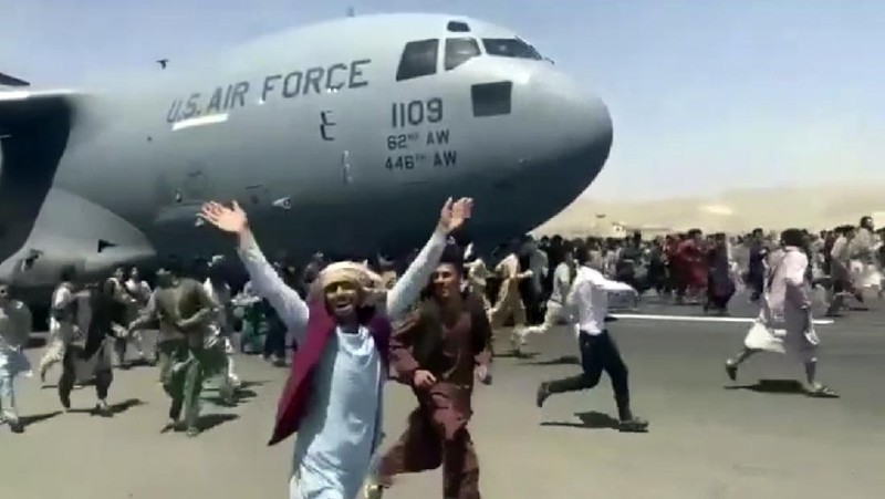 Hundreds of people run alongside a U.S. Air Force C-17 transport plane as it moves down a runway of the international airport, in Kabul, Afghanistan, Monday, Aug.16. 2021. Thousands of Afghans have rushed onto the tarmac at the airport, some so desperate to escape the Taliban capture of their country that they held onto the American military jet as it took off and plunged to death. (Verified UGC via AP)