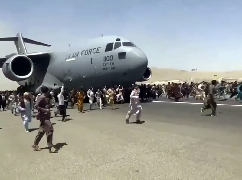 Afghanistan Hundreds of people run alongside a U.S. Air Force C-17 transport plane as it moves down a runway of the international airport, in Kabul, Afghanistan, Monday, Aug.16. 2021. Thousands of Afghans have rushed onto the tarmac at the airport, some so desperate to escape the Taliban capture of their country that they held onto the American military jet as it took off and plunged to death. (Verified UGC via AP)