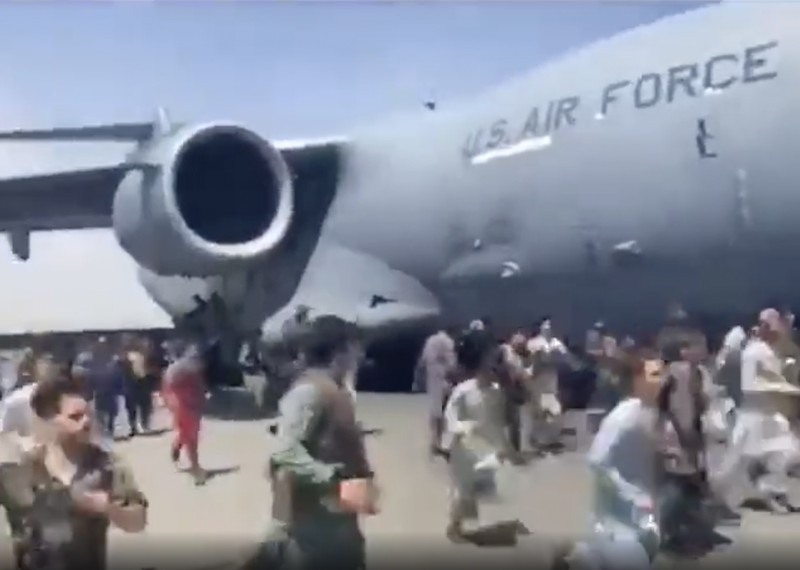 Hundreds of people run alongside a U.S. Air Force C-17 transport plane as it moves down a runway of the international airport, in Kabul, Afghanistan, Monday, Aug.16. 2021. Thousands of Afghans have rushed onto the tarmac at the airport, some so desperate to escape the Taliban capture of their country that they held onto the American military jet as it took off and plunged to death. (Verified UGC via AP)
