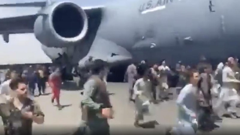 Hundreds of people run alongside a U.S. Air Force C-17 transport plane as it moves down a runway of the international airport, in Kabul, Afghanistan, Monday, Aug.16. 2021. Thousands of Afghans have rushed onto the tarmac at the airport, some so desperate to escape the Taliban capture of their country that they held onto the American military jet as it took off and plunged to death. (Verified UGC via AP)