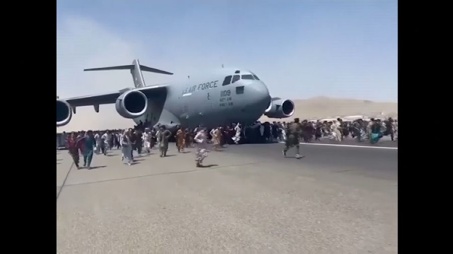 Hundreds of people run alongside a U.S. Air Force C-17 transport plane as it moves down a runway of the international airport, in Kabul, Afghanistan, Monday, Aug.16. 2021. Thousands of Afghans have rushed onto the tarmac at the airport, some so desperate to escape the Taliban capture of their country that they held onto the American military jet as it took off and plunged to death. (Verified UGC via AP)