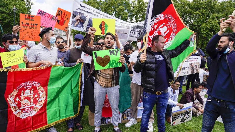 Demonstran memegang bendera Afghanistan, selama protes di Parliament Square, London, Rabu, 18 Agustus 2021. Pemerintah Inggris mengatakan pihaknya berencana untuk menerima 5.000 pengungsi Afghanistan tahun ini, terutama wanita dan anak-anak, sebagai tanggapan atas perebutan kekuasaan oleh Taliban. (AP Photo/Alberto Pezzali)