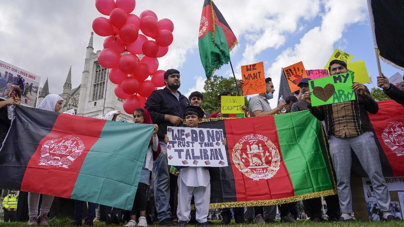 Demonstran memegang bendera Afghanistan, selama protes di Parliament Square, London, Rabu, 18 Agustus 2021. Pemerintah Inggris mengatakan pihaknya berencana untuk menerima 5.000 pengungsi Afghanistan tahun ini, terutama wanita dan anak-anak, sebagai tanggapan atas perebutan kekuasaan oleh Taliban. (AP Photo/Alberto Pezzali)