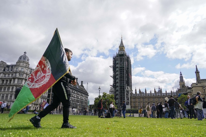 Demonstran memegang bendera Afghanistan, selama protes di Parliament Square, London, Rabu, 18 Agustus 2021. Pemerintah Inggris mengatakan pihaknya berencana untuk menerima 5.000 pengungsi Afghanistan tahun ini, terutama wanita dan anak-anak, sebagai tanggapan atas perebutan kekuasaan oleh Taliban. (AP Photo/Alberto Pezzali)