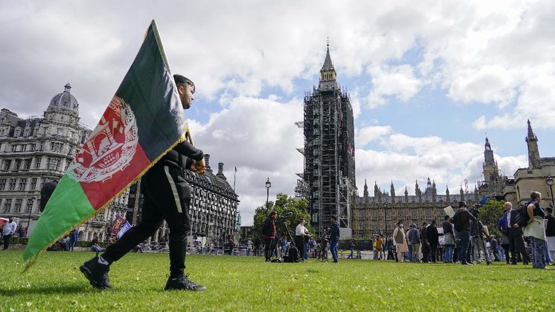 Demonstran memegang bendera Afghanistan, selama protes di Parliament Square, London, Rabu, 18 Agustus 2021. Pemerintah Inggris mengatakan pihaknya berencana untuk menerima 5.000 pengungsi Afghanistan tahun ini, terutama wanita dan anak-anak, sebagai tanggapan atas perebutan kekuasaan oleh Taliban. (AP Photo/Alberto Pezzali)