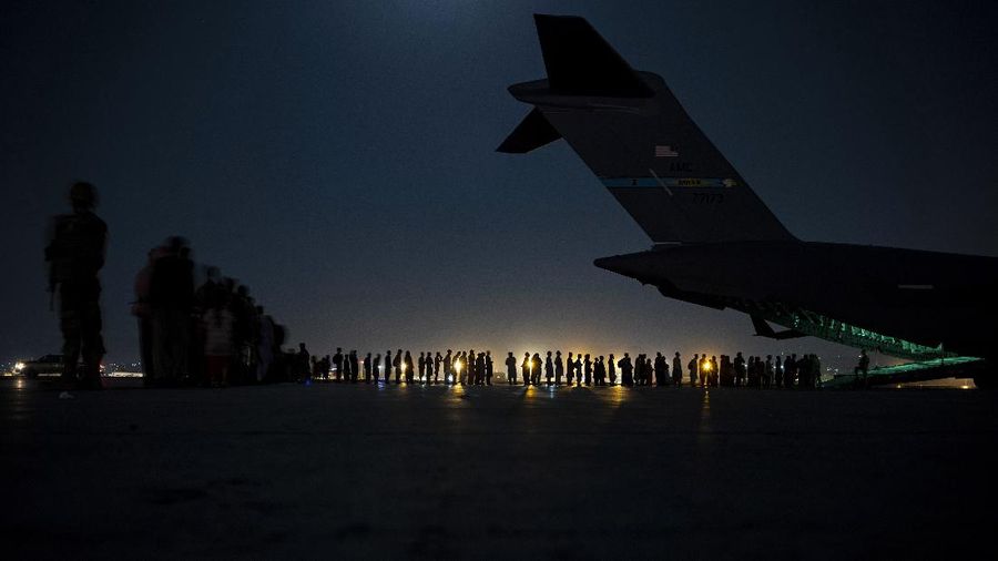 In this image provided by the U.S. Air Force, U.S. Air Force aircrew, assigned to the 816th Expeditionary Airlift Squadron, prepare to load qualified evacuees aboard a U.S. Air Force C-17 Globemaster III aircraft in support of the Afghanistan evacuation at Hamid Karzai International Airport, Kabul, Afghanistan, Saturday, Aug. 21, 2021. (Senior Airman Taylor Crul/U.S. Air Force via AP)