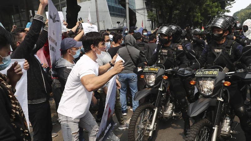 Afghan refugees  living in Indonesia shout slogans during a rally outside the building that houses UNHCR representative office in Jakarta, Indonesia, Tuesday, Aug. 24, 2021. The protesters, mostly members of the Hazara ethnic minority, held the rally on Tuesday decrying the Taliban's takeover of their country and calling for resettlement in third countries. (AP Photo/Tatan Syuflana)