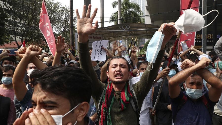 Afghan refugees  living in Indonesia shout slogans during a rally outside the building that houses UNHCR representative office in Jakarta, Indonesia, Tuesday, Aug. 24, 2021. The protesters, mostly members of the Hazara ethnic minority, held the rally on Tuesday decrying the Taliban's takeover of their country and calling for resettlement in third countries. (AP Photo/Tatan Syuflana)