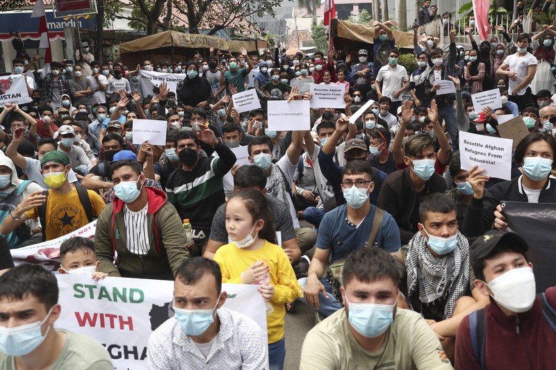 Afghan refugees  living in Indonesia shout slogans during a rally outside the building that houses UNHCR representative office in Jakarta, Indonesia, Tuesday, Aug. 24, 2021. The protesters, mostly members of the Hazara ethnic minority, held the rally on Tuesday decrying the Taliban's takeover of their country and calling for resettlement in third countries. (AP Photo/Tatan Syuflana)