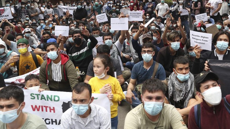 Afghan refugees  living in Indonesia shout slogans during a rally outside the building that houses UNHCR representative office in Jakarta, Indonesia, Tuesday, Aug. 24, 2021. The protesters, mostly members of the Hazara ethnic minority, held the rally on Tuesday decrying the Taliban's takeover of their country and calling for resettlement in third countries. (AP Photo/Tatan Syuflana)