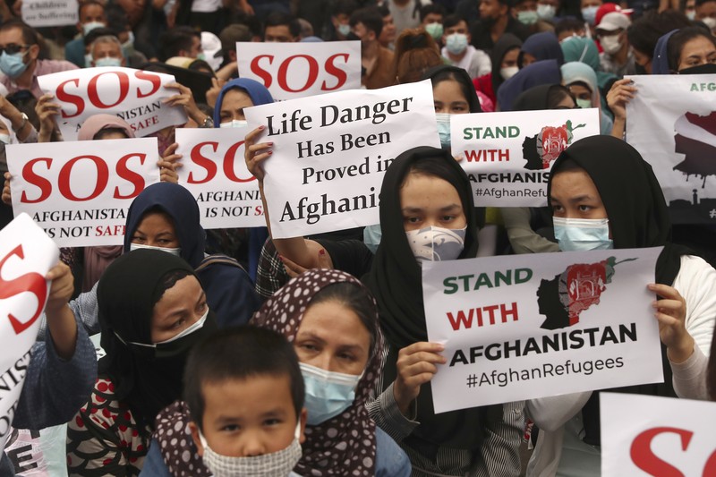 Afghan refugees  living in Indonesia shout slogans during a rally outside the building that houses UNHCR representative office in Jakarta, Indonesia, Tuesday, Aug. 24, 2021. The protesters, mostly members of the Hazara ethnic minority, held the rally on Tuesday decrying the Taliban's takeover of their country and calling for resettlement in third countries. (AP Photo/Tatan Syuflana)
