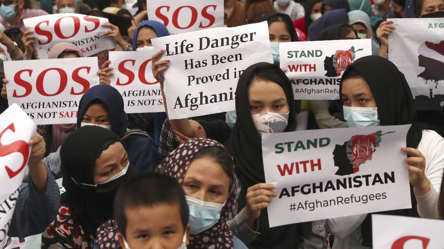 Afghan refugees living in Indonesia shout slogans during a rally outside the building that houses UNHCR representative office in Jakarta, Indonesia, Tuesday, Aug. 24, 2021. The protesters, mostly members of the Hazara ethnic minority, held the rally on Tuesday decrying the Taliban's takeover of their country and calling for resettlement in third countries. (AP Photo/Tatan Syuflana)