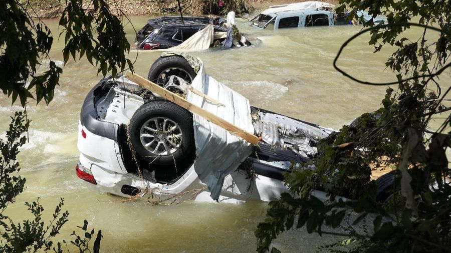 Cars are stacked on top of each other on the banks of Blue Creek being swept up in flood water, Monday, Aug. 23, 2021, in Waverly, Tenn. Heavy rains caused flooding in Middle Tennessee days ago and have resulted in multiple deaths as homes and rural roads were washed away. (AP Photo/John Amis)