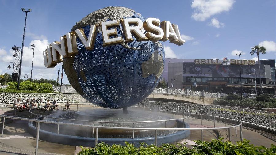 FILE - In this Thursday, Oct. 22, 2015, file photo, park guests relax and cool off with a water mist under the globe at Universal Studios City Walk in Orlando, Fla. Florida tourism officials say cases of the new coronavirus are having little visible impact on the state's biggest industry so far. Tom Schroder, a spokesman for Universal Orlando, said it is reinforcing 