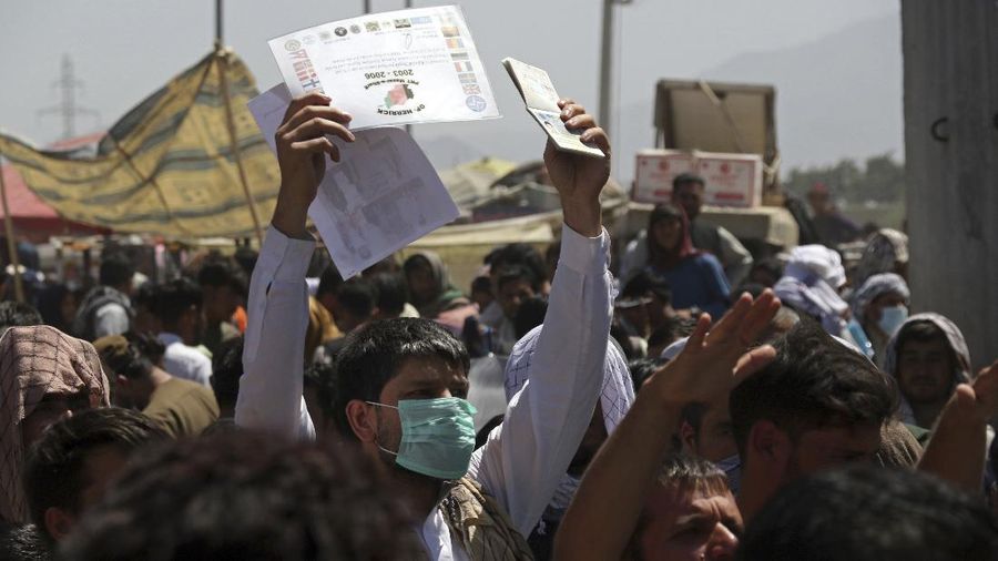 U.S. soldiers stand inside the airport as hundreds of people gather some holding documents, near an evacuation control checkpoint on the perimeter of the Hamid Karzai International Airport, in Kabul, Afghanistan, Thursday, Aug. 26, 2021. Western nations warned Thursday of a possible attack on Kabul's airport, where thousands have flocked as they try to flee Taliban-controlled Afghanistan in the waning days of a massive airlift. Britain said an attack could come within hours. (AP Photo/Wali Sabawoon)