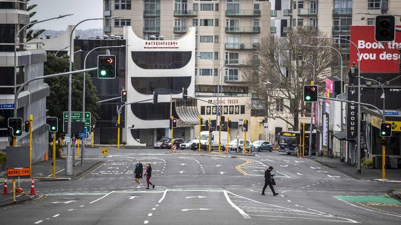 People cross nearly empty streets in the central business district of Auckland, New Zealand, Friday Aug. 27, 2021. By early next week, New Zealanders should know if their government's strict new lockdown is working to stamp out its first coronavirus outbreak in six months. A successful effort could again make the nation's virus response the envy of the world. (Michael Craig/NZ Herald via AP)