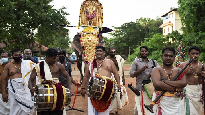 Percussion artists playing thavil, a traditional drum, walk ahead of a caparisoned elephant carrying an idol of a deity during Onam festival at the Vamana Hindu temple in Kochi, Kerala state, India, Friday, Aug.20, 2021. (AP Photo/R S Iyer)