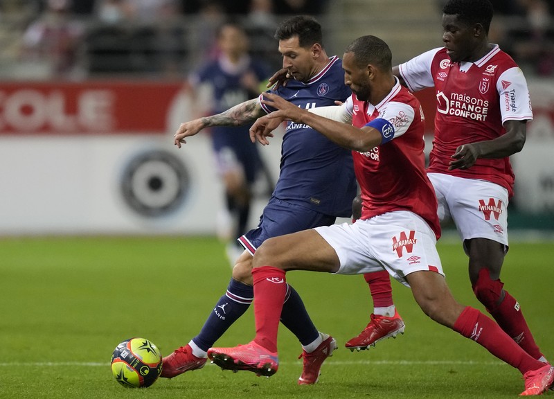 France Soccer League One Reims' Marshall Munetsi, left, challenges for the ball with PSG's Lionel Messi during the France League One soccer match between Reims and Paris Saint-Germain, at the Stade Auguste-Delaune in Reims, France, Sunday, Aug. 29, 2021. (AP Photo/Francois Mori)