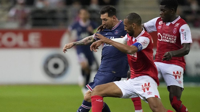 Reims' Marshall Munetsi, left, challenges for the ball with PSG's Lionel Messi during the France League One soccer match between Reims and Paris Saint-Germain, at the Stade Auguste-Delaune in Reims, France, Sunday, Aug. 29, 2021. (AP Photo/Francois Mori)
