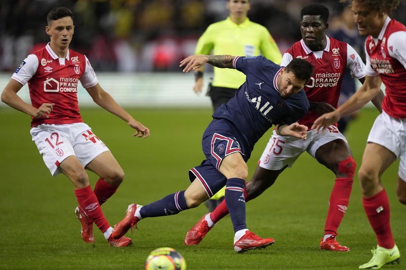 France Soccer League One Reims' Marshall Munetsi, left, challenges for the ball with PSG's Lionel Messi during the France League One soccer match between Reims and Paris Saint-Germain, at the Stade Auguste-Delaune in Reims, France, Sunday, Aug. 29, 2021. (AP Photo/Francois Mori)