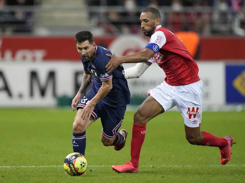 Reims' Marshall Munetsi, left, challenges for the ball with PSG's Lionel Messi during the France League One soccer match between Reims and Paris Saint-Germain, at the Stade Auguste-Delaune in Reims, France, Sunday, Aug. 29, 2021. (AP Photo/Francois Mori)