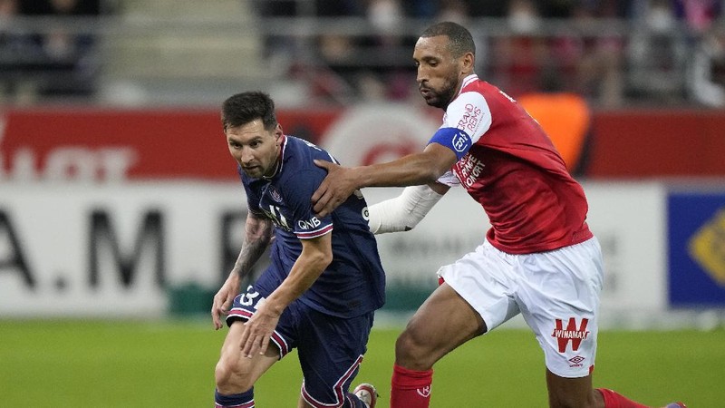 Reims' Marshall Munetsi, left, challenges for the ball with PSG's Lionel Messi during the France League One soccer match between Reims and Paris Saint-Germain, at the Stade Auguste-Delaune in Reims, France, Sunday, Aug. 29, 2021. (AP Photo/Francois Mori)