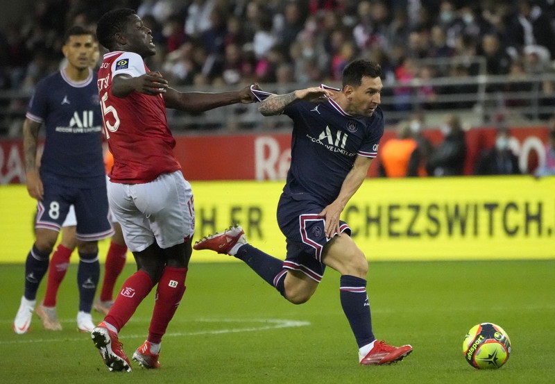 France Soccer League One Reims' Marshall Munetsi, left, challenges for the ball with PSG's Lionel Messi during the France League One soccer match between Reims and Paris Saint-Germain, at the Stade Auguste-Delaune in Reims, France, Sunday, Aug. 29, 2021. (AP Photo/Francois Mori)