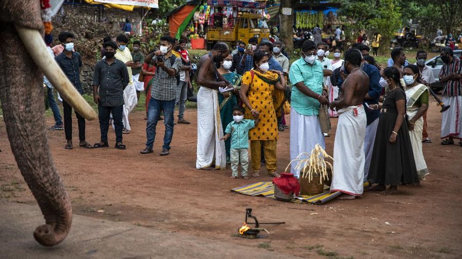 A child wearing a face mask as a precaution against the coronavirus looks at an elephant during Onam festival at the Vamana Hindu temple in Kochi, Kerala state, India, Friday, Aug.20, 2021. (AP Photo/R S Iyer)