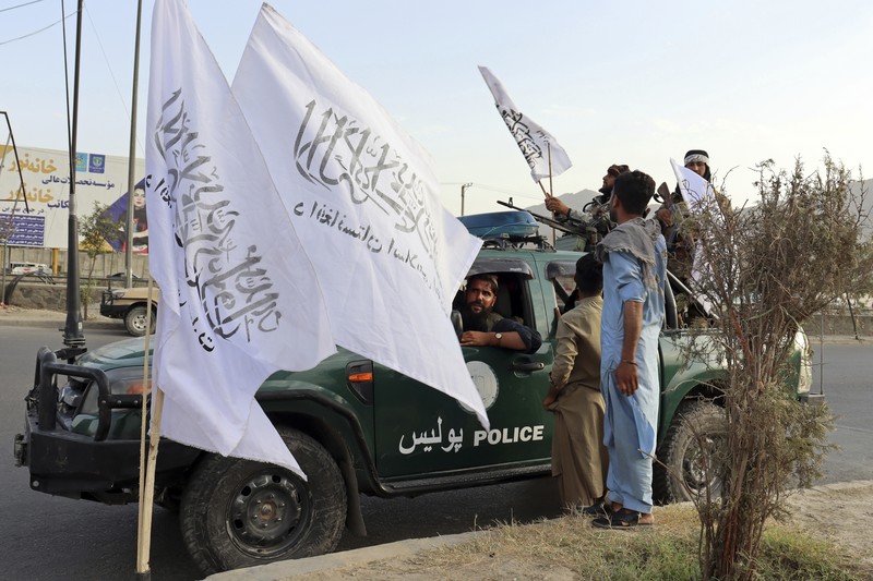 Taliban fighters hold Taliban flags in Kabul, Afghanistan, Monday, Aug. 30, 2021. Many Afghans are anxious about the Taliban rule and are figuring out ways to get out of Afghanistan. But it's the financial desperation that seems to hang heavy over the city. (AP Photo/Khwaja Tawfiq Sediqi)