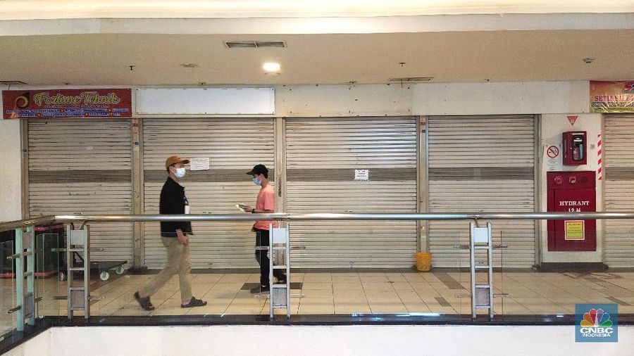 Warga melintasi ruko yang bertulisan