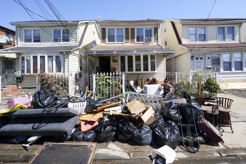 Banjir New York Akibat Badai Ida A resident of 153rd St. in the Flushing neighborhood of the Queens borough of New York sits outside her home with her water logged belongings, Thursday, Sept. 2, 2021, in New York. The remnants of Hurricane Ida dumped historic rain over New York City, with several deaths linked to flooding in the region as basement apartments suddenly filled with water and freeways and boulevards turned into rivers, submerging cars.(AP Photo/Mary Altaffer)