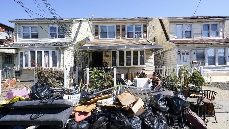 A resident of 153rd St. in the Flushing neighborhood of the Queens borough of New York sits outside her home with her water logged belongings, Thursday, Sept. 2, 2021, in New York. The remnants of Hurricane Ida dumped historic rain over New York City, with several deaths linked to flooding in the region as basement apartments suddenly filled with water and freeways and boulevards turned into rivers, submerging cars.(AP Photo/Mary Altaffer)