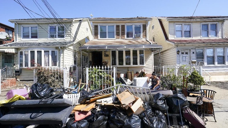 A resident of 153rd St. in the Flushing neighborhood of the Queens borough of New York sits outside her home with her water logged belongings, Thursday, Sept. 2, 2021, in New York. The remnants of Hurricane Ida dumped historic rain over New York City, with several deaths linked to flooding in the region as basement apartments suddenly filled with water and freeways and boulevards turned into rivers, submerging cars.(AP Photo/Mary Altaffer)
