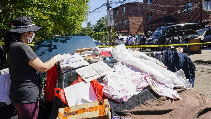 A resident of 153rd St. in the Flushing neighborhood of the Queens borough of New York sits outside her home with her water logged belongings, Thursday, Sept. 2, 2021, in New York. The remnants of Hurricane Ida dumped historic rain over New York City, with several deaths linked to flooding in the region as basement apartments suddenly filled with water and freeways and boulevards turned into rivers, submerging cars.(AP Photo/Mary Altaffer)