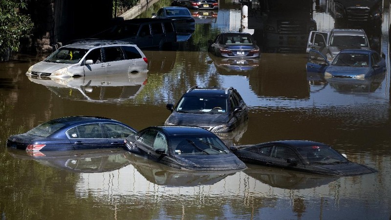 A resident of 153rd St. in the Flushing neighborhood of the Queens borough of New York sits outside her home with her water logged belongings, Thursday, Sept. 2, 2021, in New York. The remnants of Hurricane Ida dumped historic rain over New York City, with several deaths linked to flooding in the region as basement apartments suddenly filled with water and freeways and boulevards turned into rivers, submerging cars.(AP Photo/Mary Altaffer)