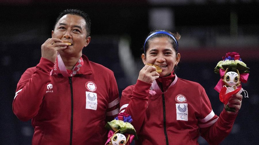 Hary Susanto dari Indonesia, kiri, dan Leani Ratri Oktila berfoto setelah menerima medali emas untuk pertandingan perebutan medali emas ganda campuran SL3-SU5 di Paralympic Games Tokyo 2020, Minggu, (5/9/2021) di Tokyo, Jepang. (AP/Kiichiro Sato)