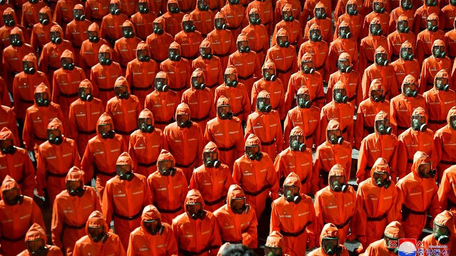 Parade militer besar-besaran Korut yang terbaru menampilkan barisan personel yang memakai baju hazmat warna oranye. (via REUTERS/KCNA)