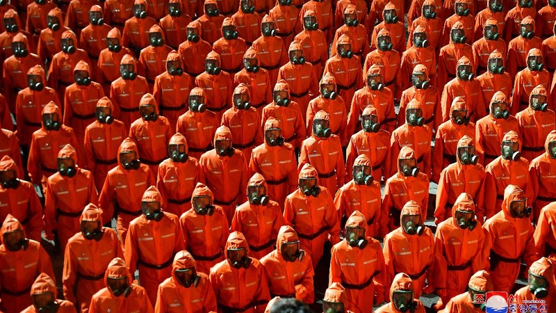 Parade militer besar-besaran Korut yang terbaru menampilkan barisan personel yang memakai baju hazmat warna oranye. (via REUTERS/KCNA)