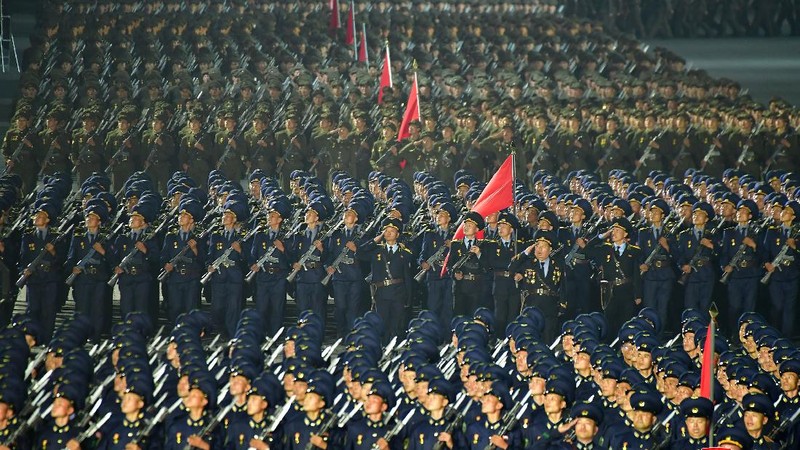 Parade militer besar-besaran Korut yang terbaru menampilkan barisan personel yang memakai baju hazmat warna oranye. (via REUTERS/KCNA)