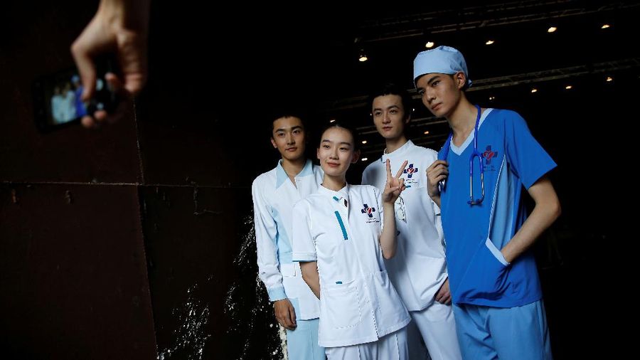 Models in medical creations pose for pictures while they wait backstage before a fashion show with creations for medical professionals, designed by the Beijing Institute of Fashion Technology in collaboration with Dishang, during China Fashion Week in Beijing, China September 11, 2021. REUTERS/Tingshu Wang