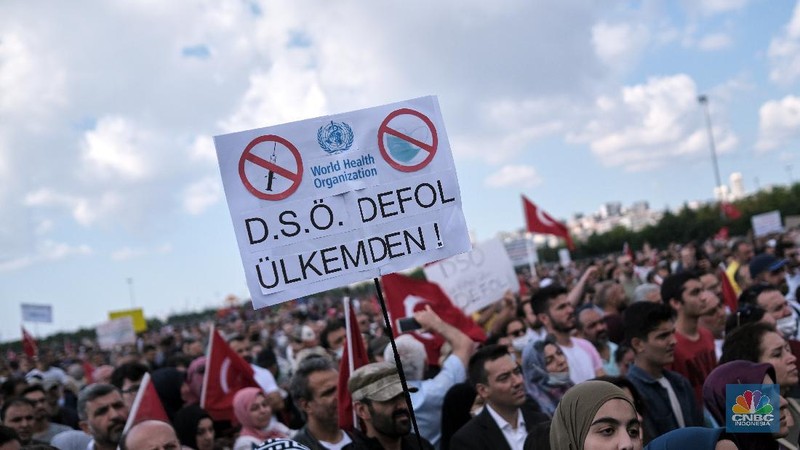 A demonstrator holds a placard reading 