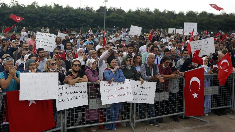 A demonstrator holds a placard reading 