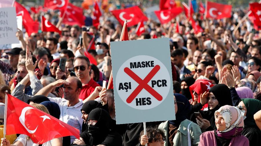 A boy holds a placard as anti-vaccine demonstrators wave Turkish flags during a protest against official coronavirus disease (COVID-19)-related mandates, including vaccinations, tests and masks, in Istanbul, Turkey September 11, 2021. REUTERS/Murad Sezer