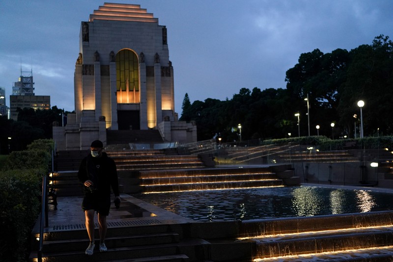 HEALTH-CORONAVIRUS/AUSTRALIA A pedestrian crosses a street at sunset in the city centre during a lockdown to curb the spread of a coronavirus disease (COVID-19) outbreak in Sydney, Australia, September 14, 2021. REUTERS/Loren Elliott TPX IMAGES OF THE DAY