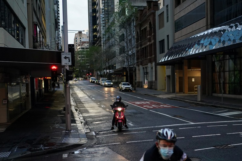 HEALTH-CORONAVIRUS/AUSTRALIA A pedestrian crosses a street at sunset in the city centre during a lockdown to curb the spread of a coronavirus disease (COVID-19) outbreak in Sydney, Australia, September 14, 2021. REUTERS/Loren Elliott TPX IMAGES OF THE DAY