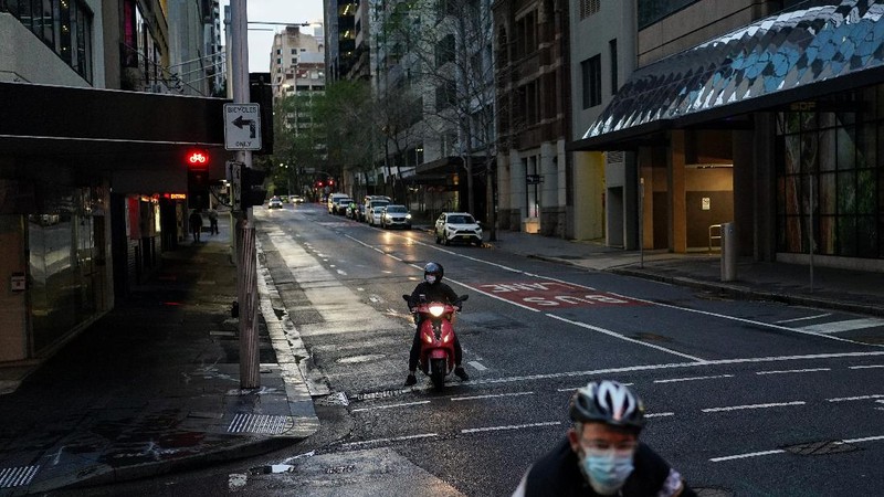 A pedestrian crosses a street at sunset in the city centre during a lockdown to curb the spread of a coronavirus disease (COVID-19) outbreak in Sydney, Australia, September 14, 2021.  REUTERS/Loren Elliott     TPX IMAGES OF THE DAY